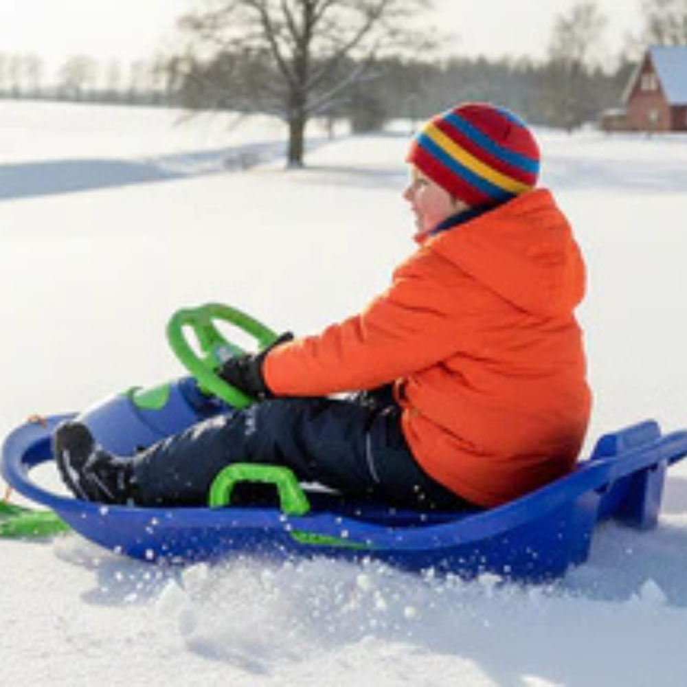 dreng kører i snowrider bobslæde med rat og bremser i sne